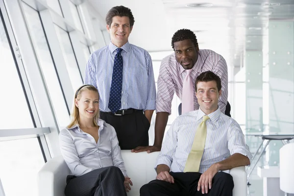 Четыре бизнесмена в офисном холле улыбаются — стоковое фото