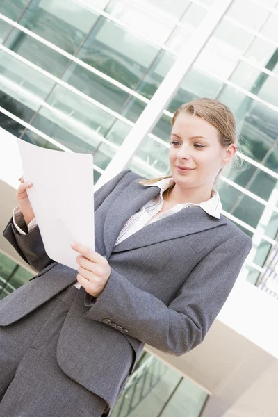 Geschäftsfrau steht draußen und liest Papierkram — Stockfoto