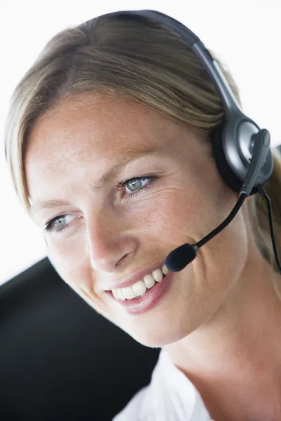 Mujer de negocios en la oficina con auriculares y sonriendo —  Fotos de Stock