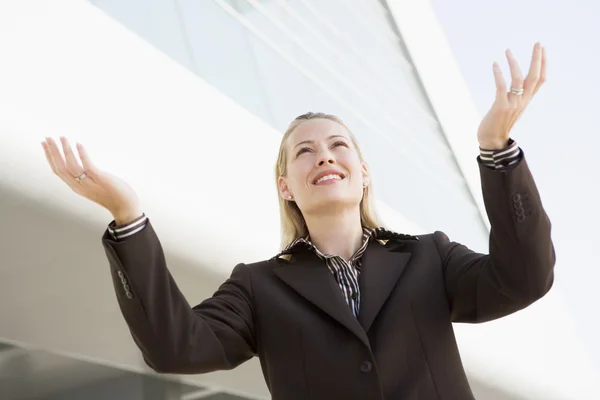 Businesswoman standing outdoors by building with hands out smili — Stock Photo, Image