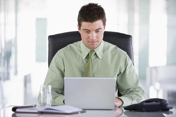 Бизнесмен, сидящий в офисе с личным органайзером и ноутбуком — стоковое фото
