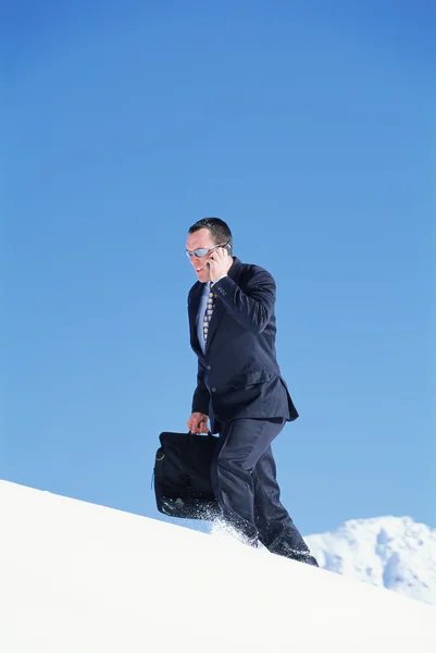 Geschäftsmann mit Handy auf schneebedecktem Berg unterwegs — Stockfoto