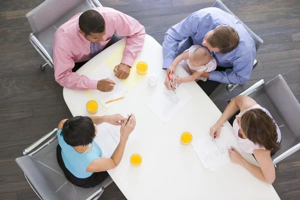 Four businesspeople in boardroom with one holding a baby — Stock Photo, Image