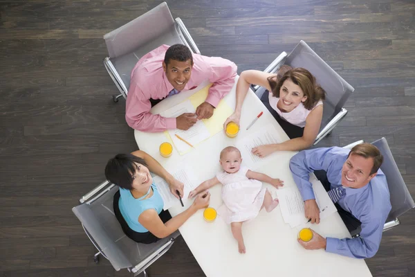 Quatro empresários na sala de reuniões com um bebê deitado na mesa — Fotografia de Stock
