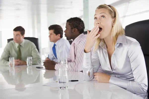 Cuatro empresarios en la sala de juntas con una mujer de negocios bostezando —  Fotos de Stock