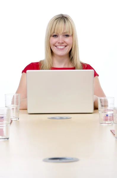 Kobieta siedzi w sali konferencyjnej z laptopa uśmiechający się — Zdjęcie stockowe