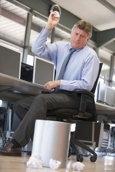 Businessman in office space throwing garbage in bin — Stock Photo, Image