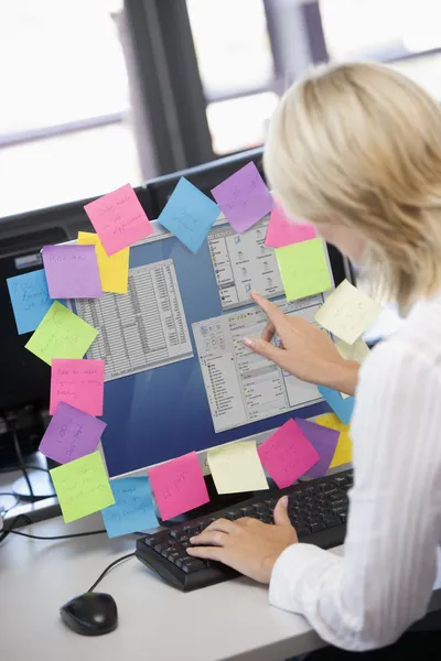 stock image Businesswoman in office pointing at monitor with notes on it