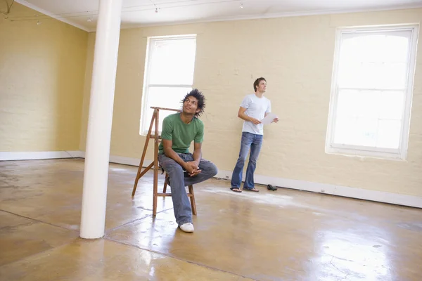 Deux hommes dans un espace vide avec une échelle tenant du papier — Photo