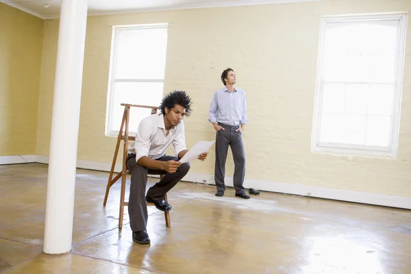 stock image Man sitting on ladder in empty space holding paper with other ma