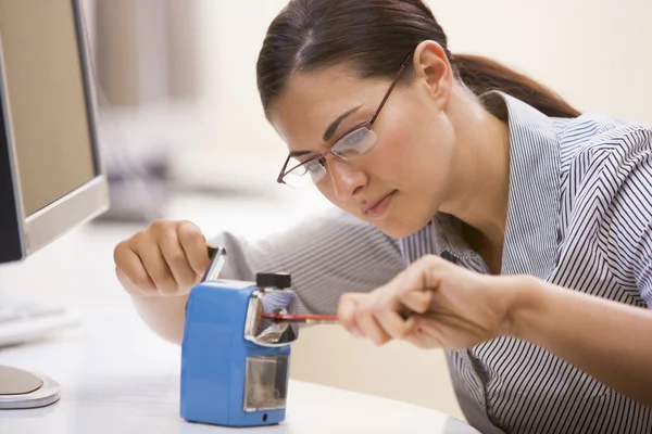Woman in computer room using pencil sharpener — Stock Photo, Image
