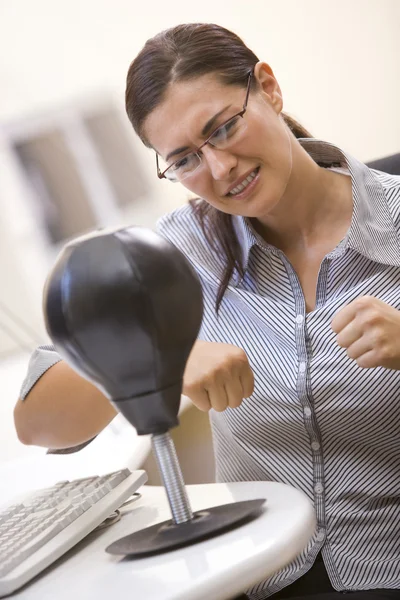 Женщина в компьютерной комнате использует маленькую боксерскую грушу для снятия стресса — стоковое фото