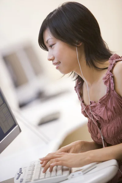 Γυναίκα Στο Δωμάτιο Του Υπολογιστή Ακούγοντας Mp3 Player Ενώ Πληκτρολογείτε — Φωτογραφία Αρχείου