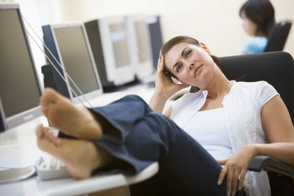 Mulher na sala de informática com os pés para cima pensando — Fotografia de Stock