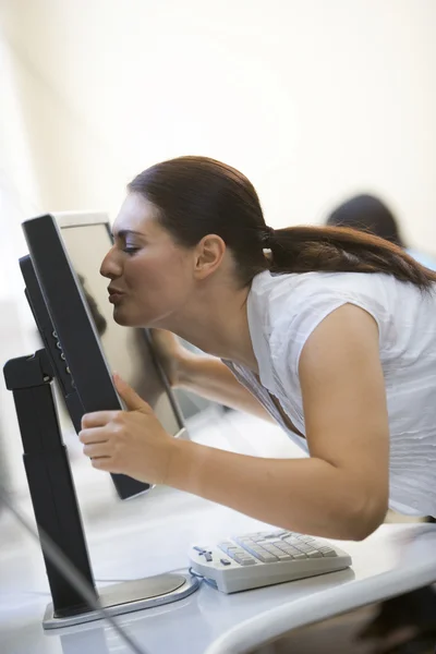 Žena v počítačové místnosti líbání monitoru — Stock fotografie
