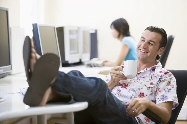 Ember a számítógépes teremben a láb fel kávét iszik, és mosolyogva — Stock Fotó