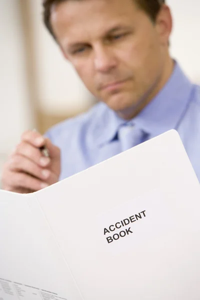 Empresario en el interior mirando libro de accidentes — Foto de Stock