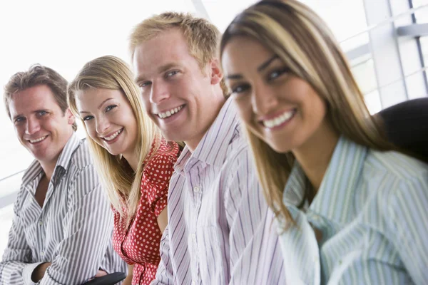 Vier ondernemers zitten binnenshuis glimlachen — Stockfoto