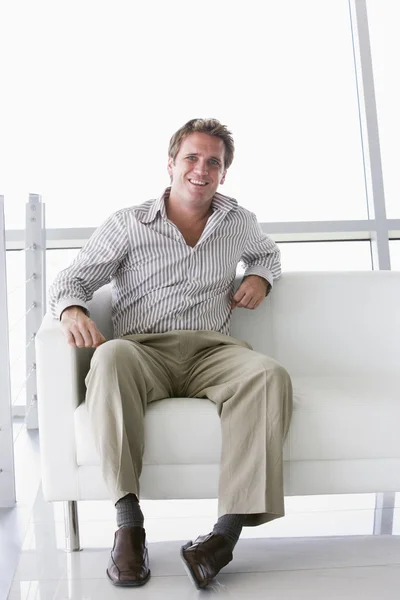 Бізнесмен, сидячи в офісному вестибюлі посміхається — стокове фото