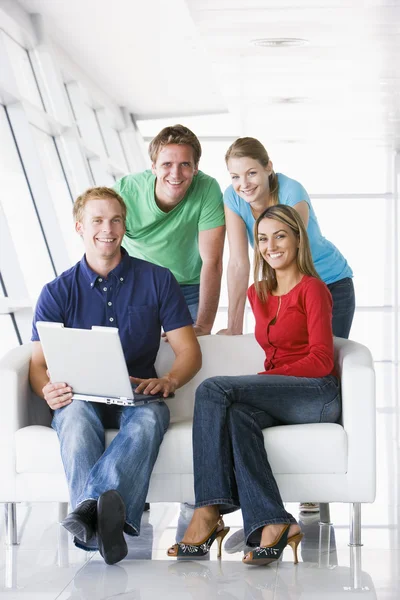 Vier in lobby met laptop glimlachen — Stockfoto