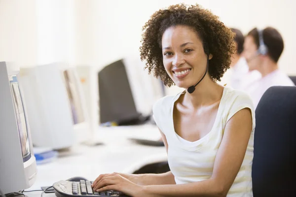 Woman wearing headset in computer room smiling — Stock Photo, Image