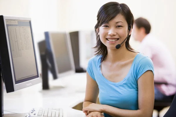 Mujer con auriculares en la sala de computadoras sonriendo — Foto de Stock
