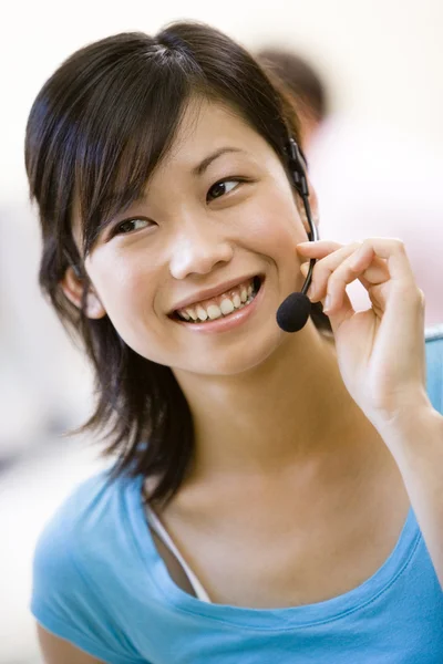 Woman wearing headset indoors smiling — Stock Photo, Image