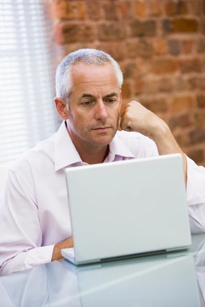 Businessman sitting in office on laptop — Stock Photo, Image