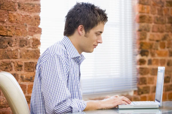 Businessman sitting in office with laptop — Stock Photo, Image