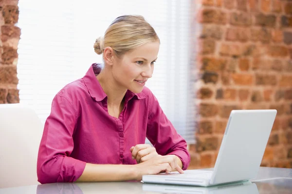 笑みを浮かべてノート パソコンを使用してオフィスに座っている女性実業家 — ストック写真