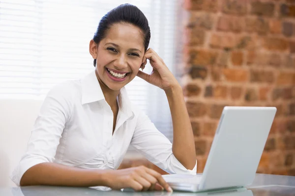 Affärskvinna i kontor med laptop skrattar — Stockfoto