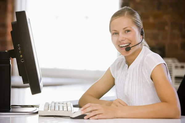 Mulher de negócios usando fone de ouvido sentado no escritório sorrindo — Fotografia de Stock