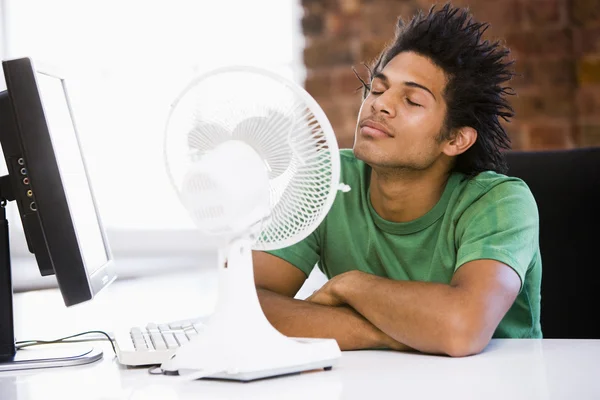Homme d'affaires au bureau avec ordinateur et ventilateur de refroidissement — Photo