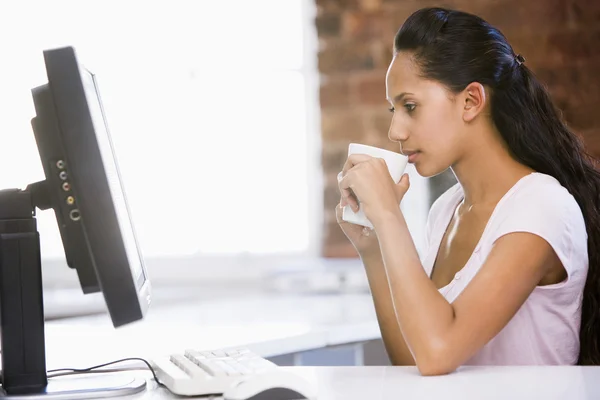 在办公室喝咖啡 看着计算机的女商人 — 图库照片