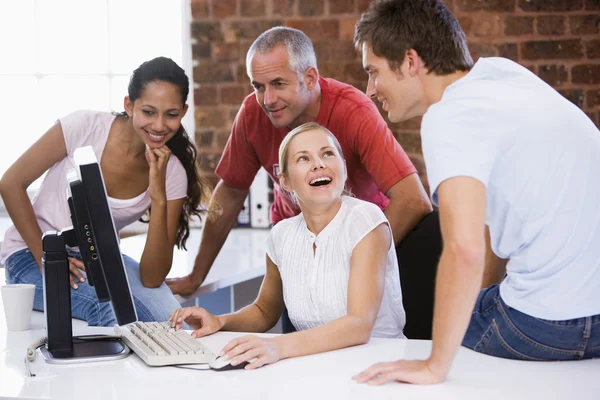 Cztery biznesmeni w przestrzeni biurowej z komputera uśmiechający się — Zdjęcie stockowe