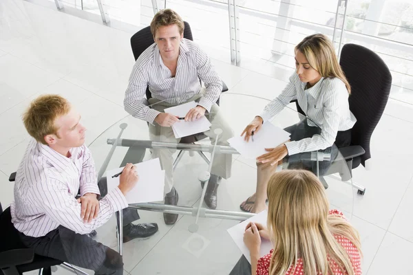 Vier Geschäftsleute im Sitzungssaal mit Papierkram — Stockfoto