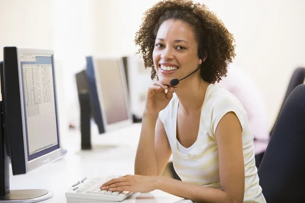 コンピューター ルームの笑顔でヘッドセットを着ている女性 — ストック写真