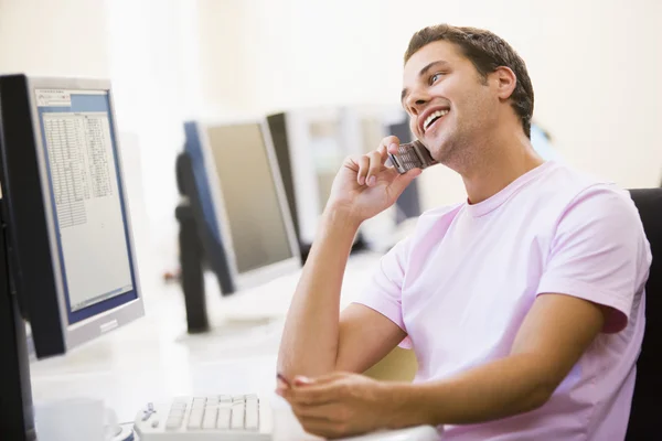 Człowiek Siedzi Sali Komputerowej Przy Użyciu Telefonu Komórkowego Uśmiechając Się — Zdjęcie stockowe