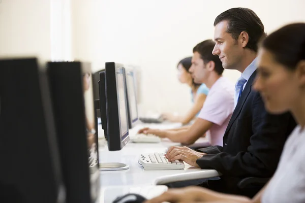 Quatro sentado na sala de informática digitando com um homem em um su — Fotografia de Stock