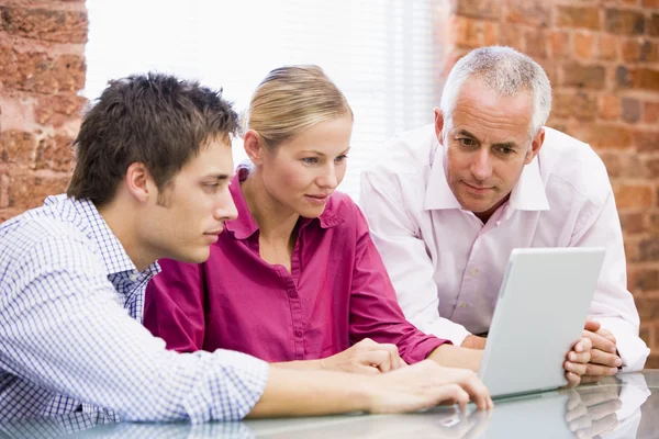 Tres empresarios en la oficina mirando a la computadora portátil — Foto de Stock