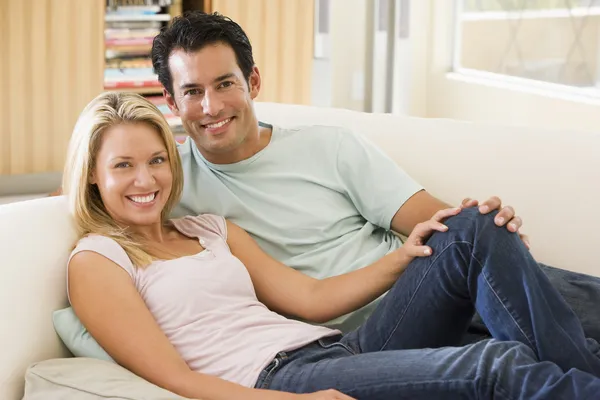 Par i vardagsrum läsa tidningen och ler — Stockfoto