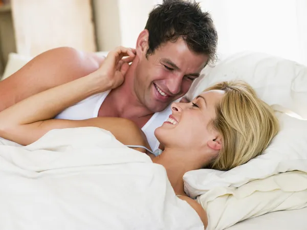 男性と女性の笑みを浮かべてベッドで目を覚まし — ストック写真