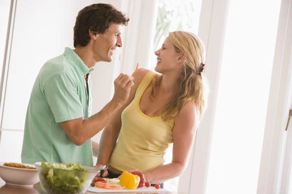 Couple en cuisine découpant des légumes et souriant — Photo