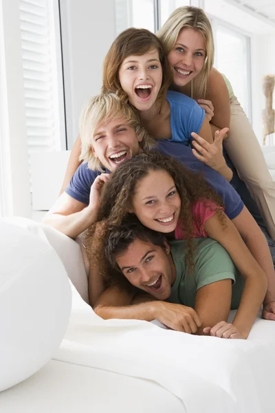 Cinco na sala de estar empilhados sorrindo — Fotografia de Stock