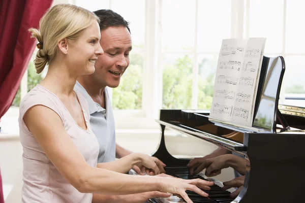 Пара, играющая на пианино и улыбающаяся — стоковое фото