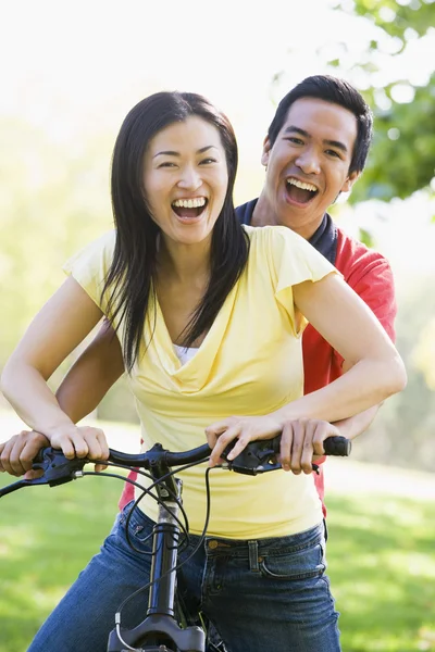 Ζευγάρι σε ένα ποδήλατο που είναι χαμογελώντας σε εξωτερικούς χώρους — Φωτογραφία Αρχείου