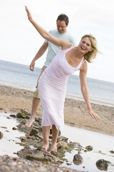 Casal na praia andando sobre pedras e sorrindo — Fotografia de Stock