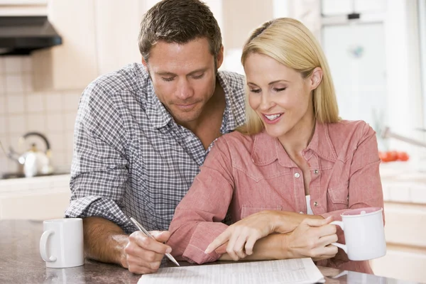 Par i köket med tidning och kaffe leende — Stockfoto