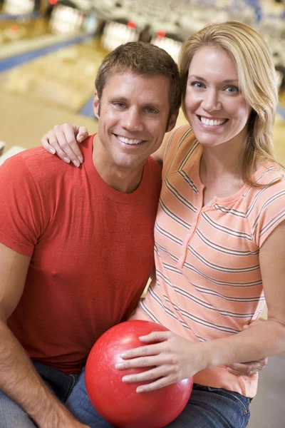 Couple in bowling alley holding ball and smiling — Stock Photo, Image