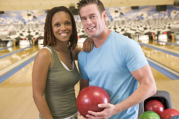 Couple in bowling alley holding ball and smiling — Stock Photo, Image